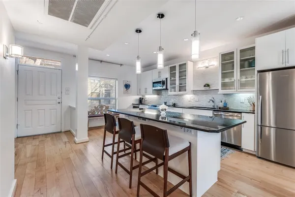 a kitchen with stainless steel appliances granite countertop a table chairs stove a sink dishwasher a refrigerator and cabinets with wooden floor