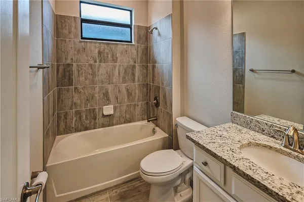 a bathroom with a granite countertop toilet sink and bathtub
