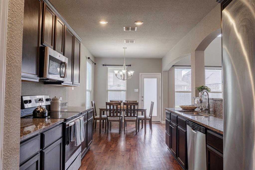2716 Beutel Road Lorena, TX 76655 - Photo 7 of 39 a kitchen with stainless steel appliances granite countertop a stove top oven a sink dishwasher a dining table and chairs with wooden floor