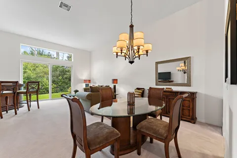 a view of a dining room with furniture a chandelier and a window