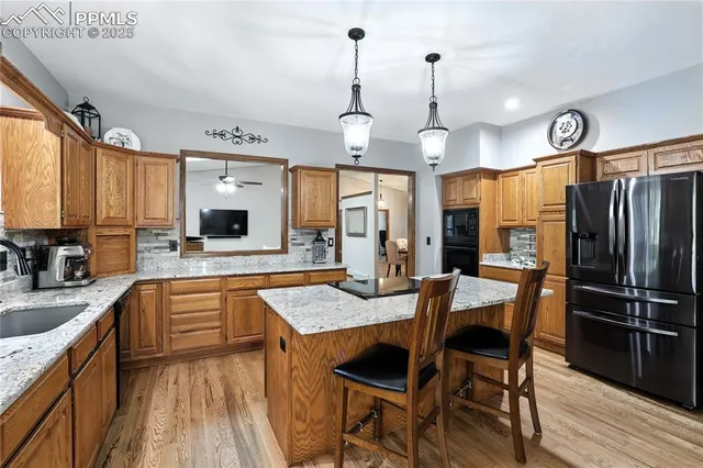 a kitchen with stainless steel appliances granite countertop a kitchen island hardwood floor sink stove dining table and chairs
