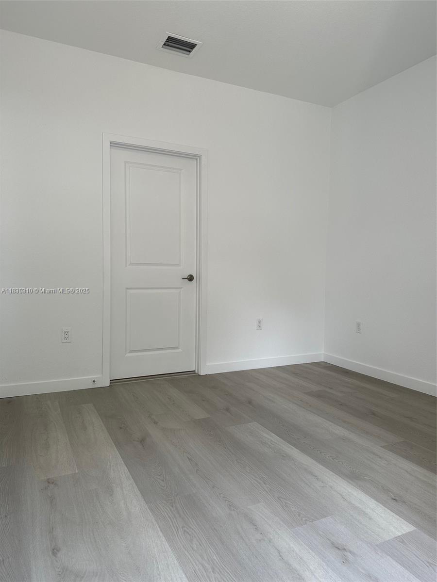 25338 Southwest 135th Avenue, Unit 107 Homestead, FL 33032 - Photo 11 of 26 an empty room with wooden floor and closet