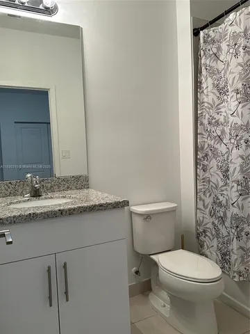 a bathroom with a granite countertop toilet sink and mirror