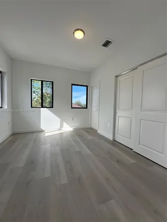 an empty room with windows and closet