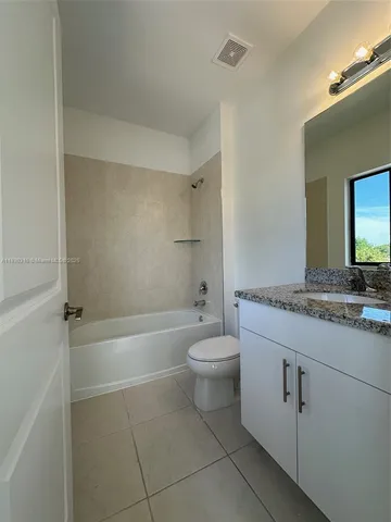 a bathroom with a granite countertop toilet a sink and bathtub
