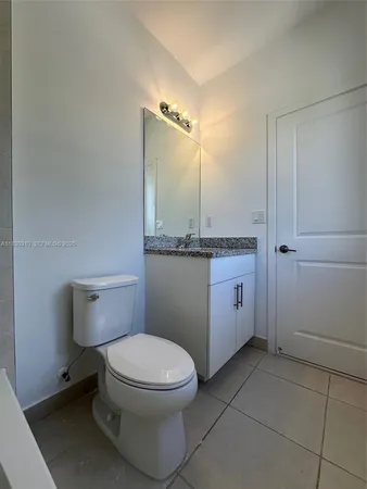 a bathroom with a granite countertop toilet and a sink
