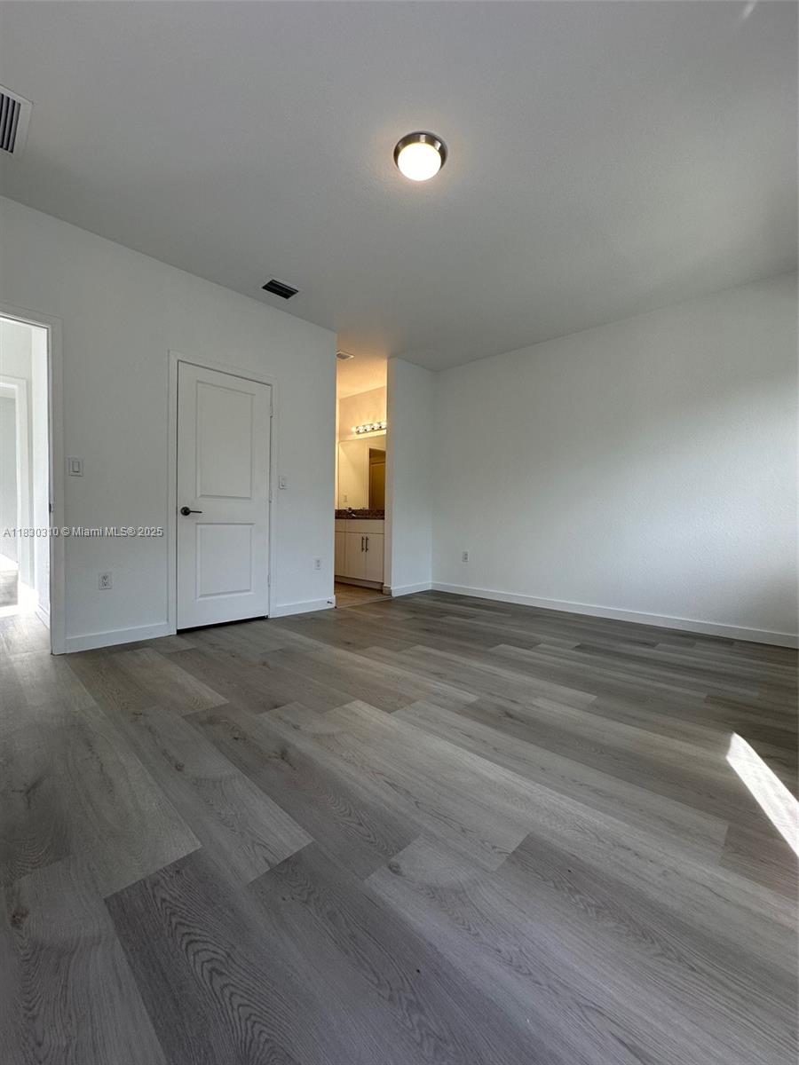 25338 Southwest 135th Avenue, Unit 107 Homestead, FL 33032 - Photo 21 of 26 a view of empty room with window and wooden floor