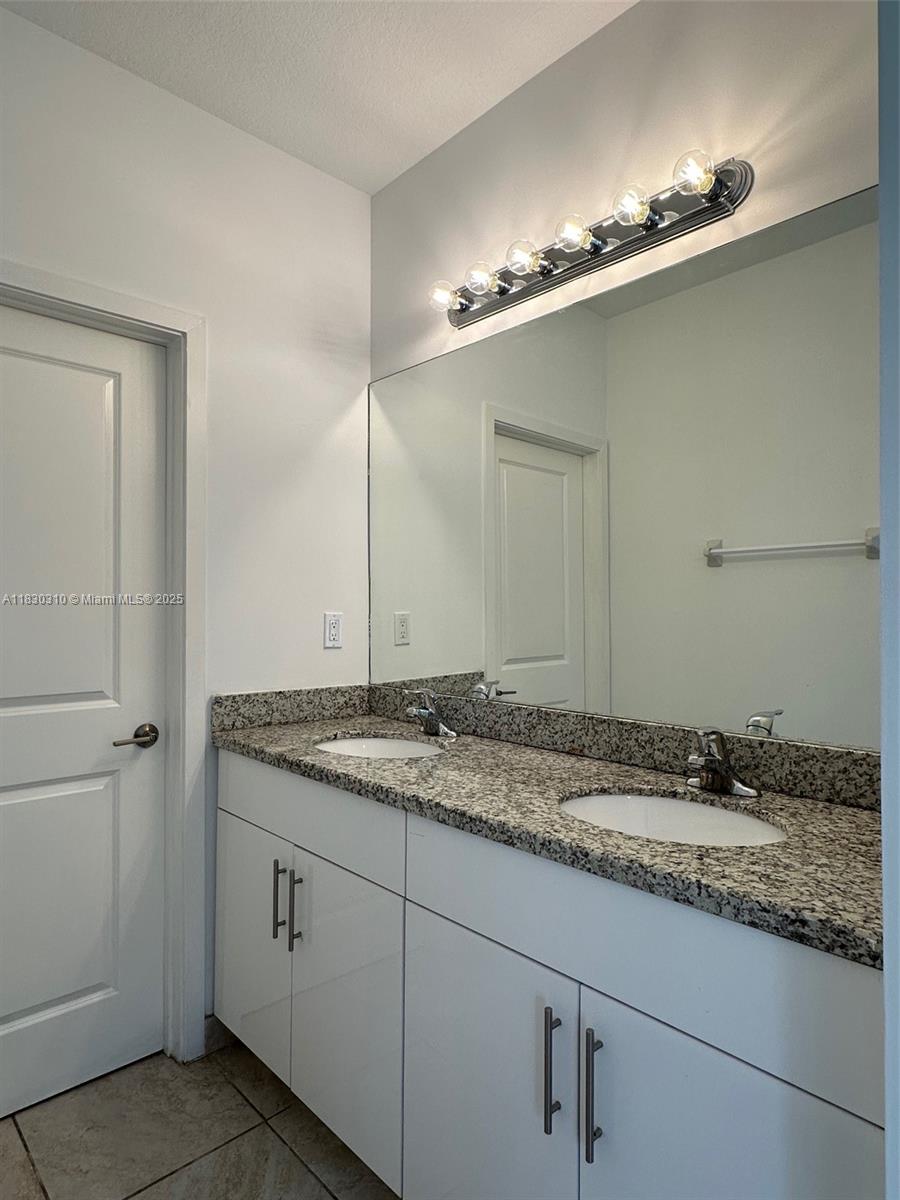 25338 Southwest 135th Avenue, Unit 107 Homestead, FL 33032 - Photo 23 of 26 a bathroom with a granite countertop sink and white cabinets