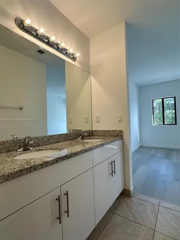 a bathroom with a granite countertop sink and a mirror
