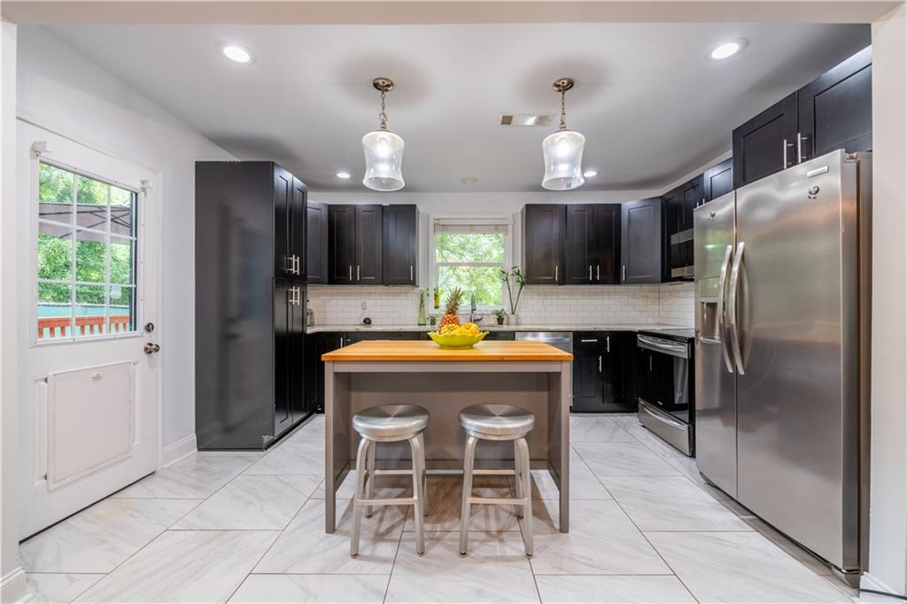 1760 Rogers Avenue Southwest Atlanta, GA 30310 - Photo 16 of 57 a kitchen with granite countertop a center island a window and stainless steel appliances