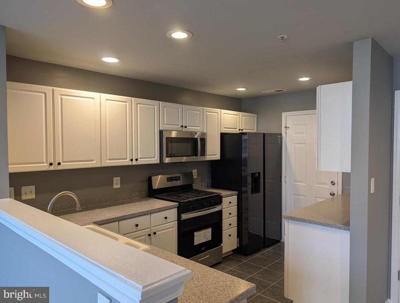 1891 Crescent Park Drive, Unit 110A Reston, VA 20190 - Photo 8 of 41 a kitchen with stainless steel appliances a refrigerator a sink a stove a microwave and wooden cabinets