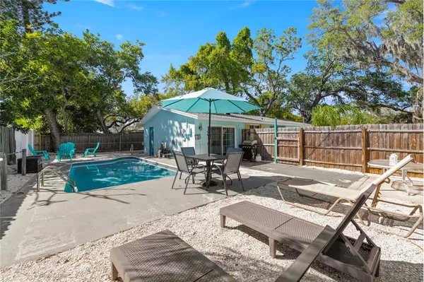 a view of a patio with a table and chairs under an umbrella with large trees