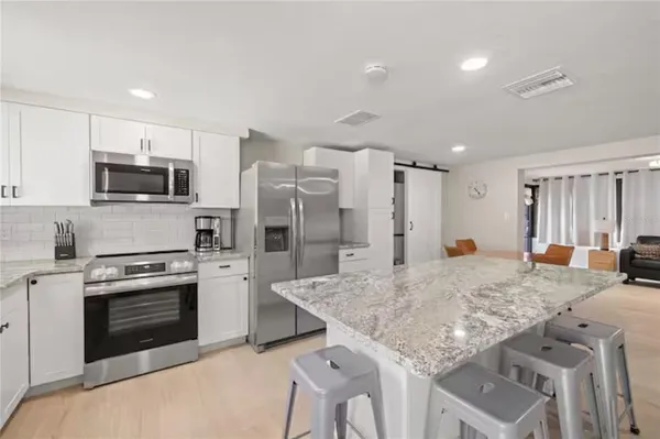 a kitchen with stainless steel appliances granite countertop a stove refrigerator sink and microwave