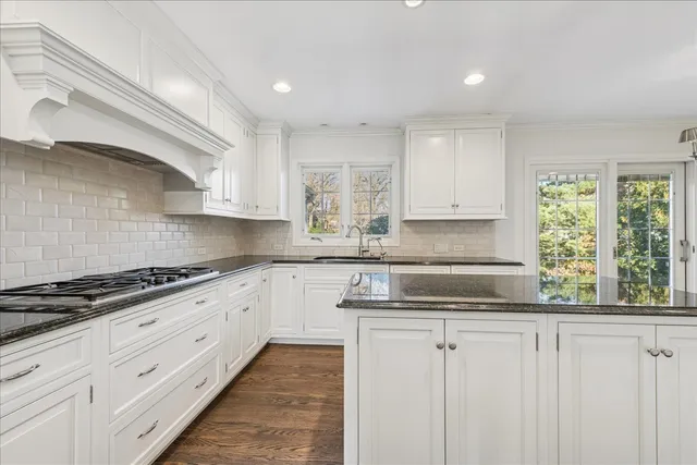 a kitchen with granite countertop white cabinets and window