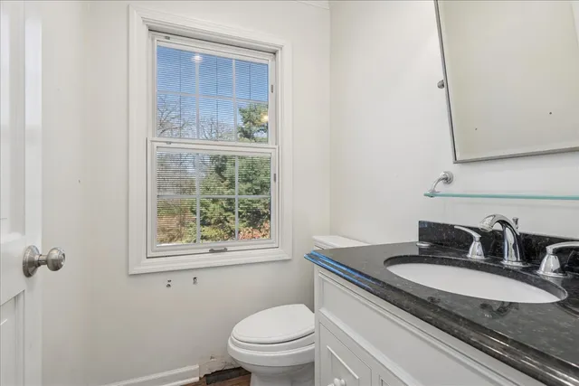 a bathroom with a granite countertop sink toilet and mirror
