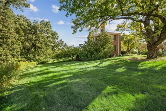 a view of a white house with a big yard and large tree