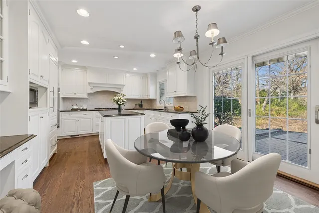 a kitchen with stainless steel appliances granite countertop a sink a stove a dining table and chairs