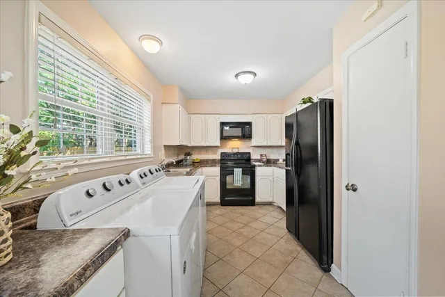 a kitchen with stainless steel appliances granite countertop a refrigerator a sink a stove and white cabinets with wooden floor