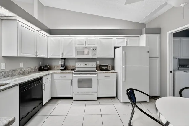 a kitchen with a refrigerator a stove a sink and white cabinets