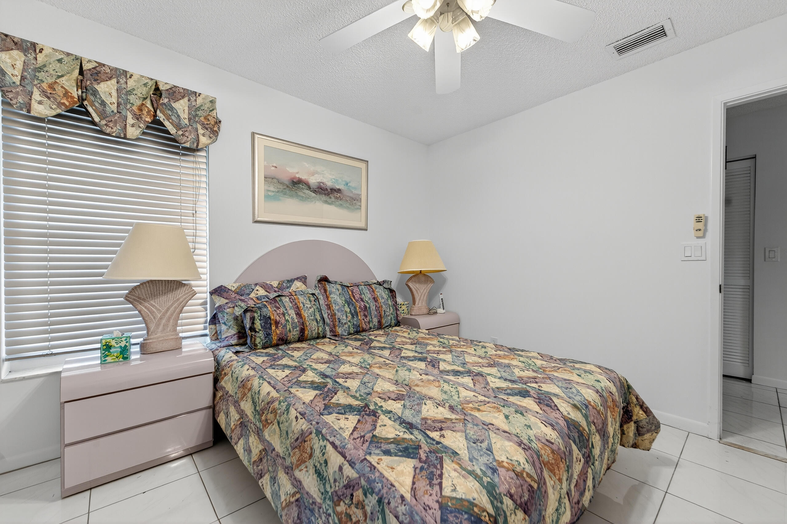 6065 Sunny Manor Court Delray Beach, FL 33484 - Photo 15 of 58 a bed sitting in a bedroom next to a window and a chandelier
