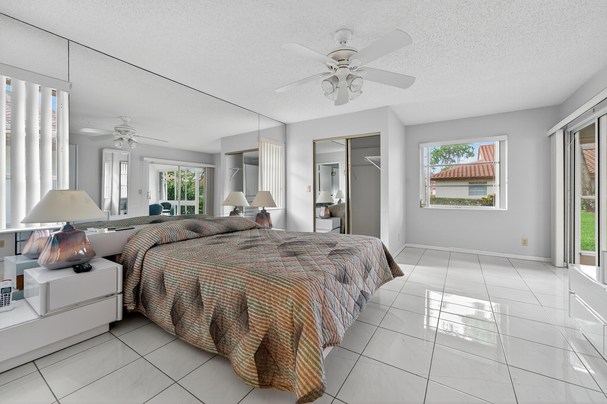 6065 Sunny Manor Court Delray Beach, FL 33484 - Photo 16 of 58 a spacious bedroom with a bed a chandelier and large window