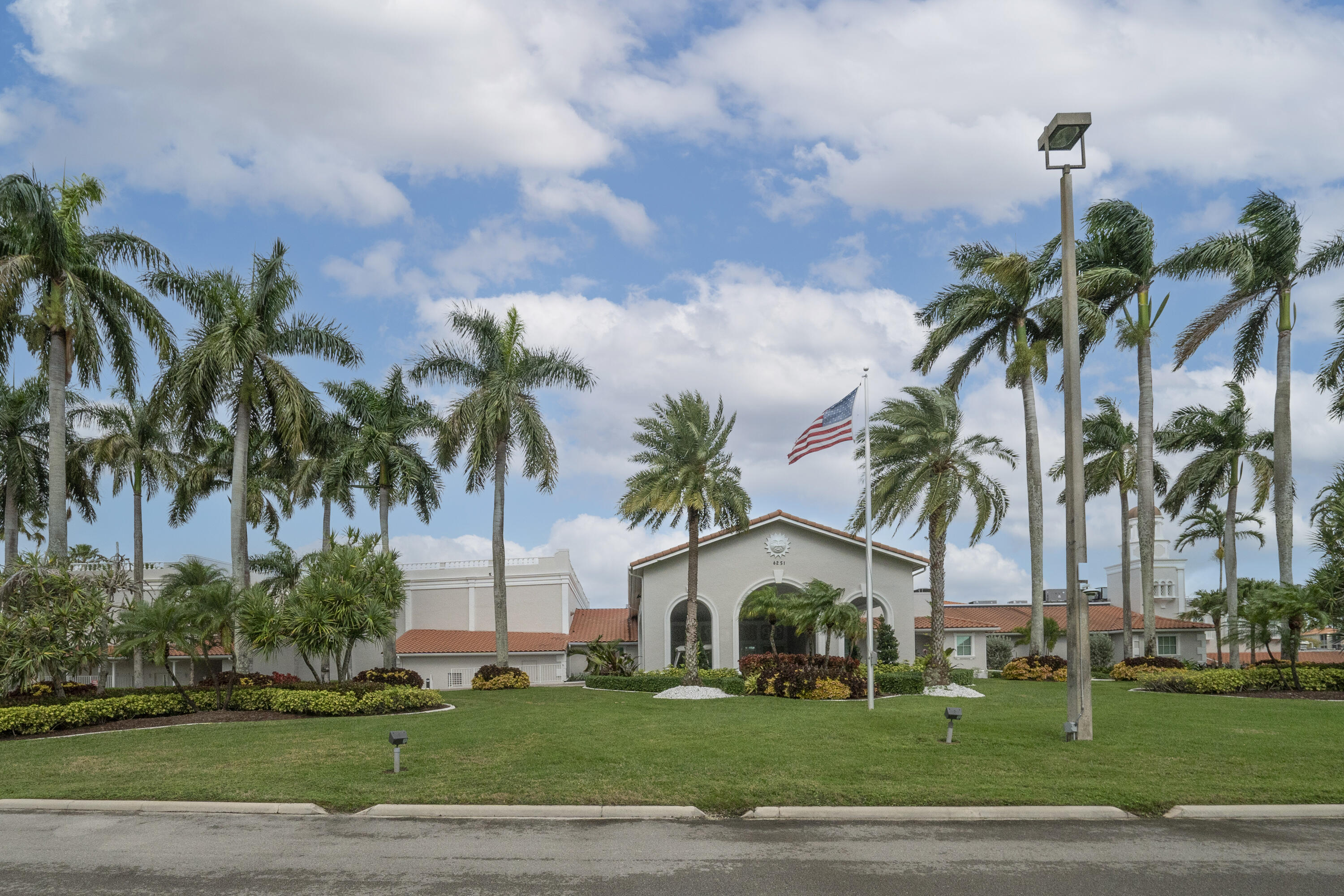 6065 Sunny Manor Court Delray Beach, FL 33484 - Photo 57 of 58 a palm tree sitting in front of a white house with a yard and palm trees