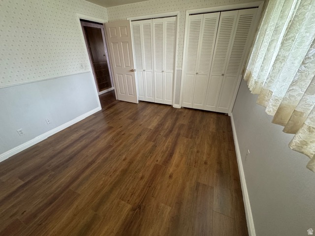 588 North 4500 West West Point, UT 84015 - Photo 21 of 61 Unfurnished bedroom featuring two closets, dark wood-style laminate flooring, and wallpapered walls