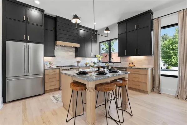 a kitchen with a refrigerator a stove a sink and a dining table with wooden floor