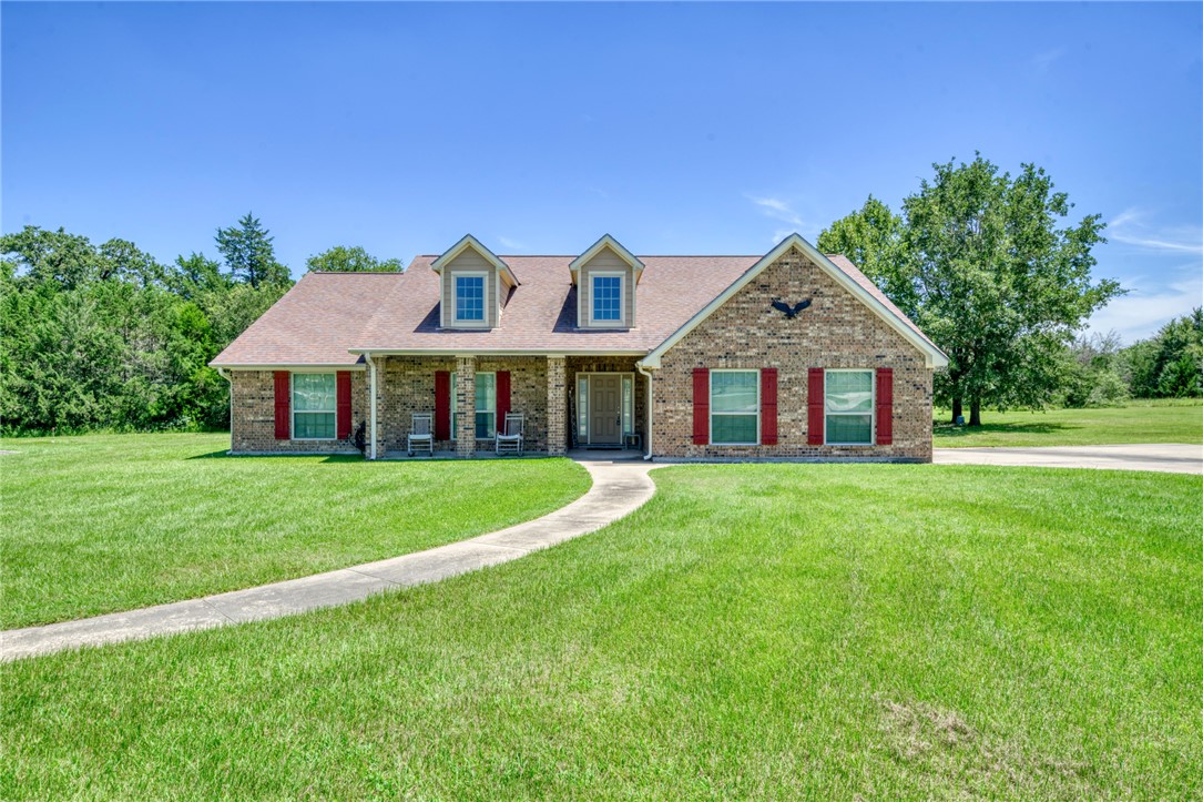 9945 Oxford Cemetery Road Madisonville, TX 77864 - Photo 5 of 42 Cape cod house featuring a porch, a front lawn, brick siding, and a shingled roof