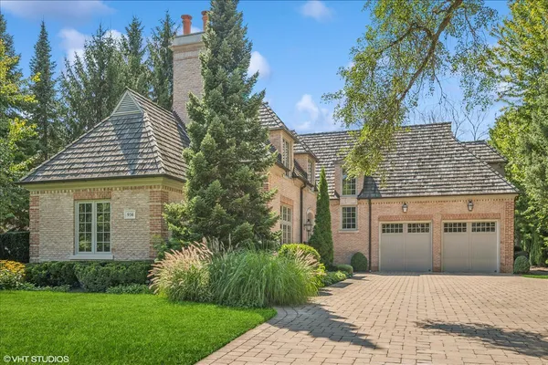 a front view of a house with a garden and trees