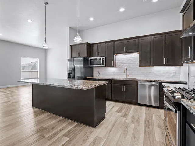 a large kitchen with stainless steel appliances granite countertop a stove a sink and a refrigerator