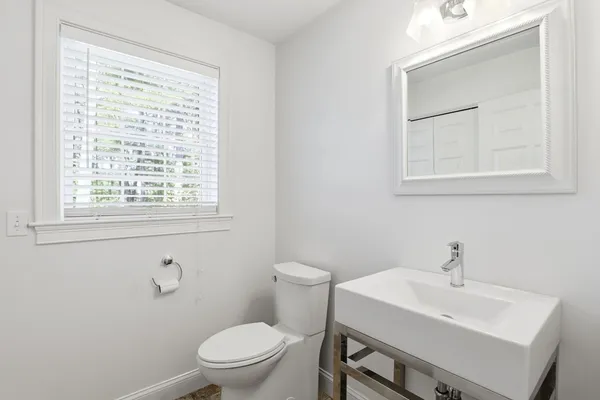 a bathroom with a toilet a sink a mirror and a window