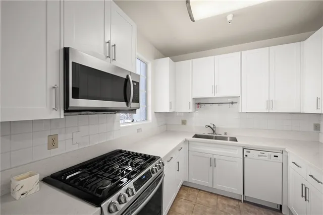 a kitchen with white cabinets and appliances