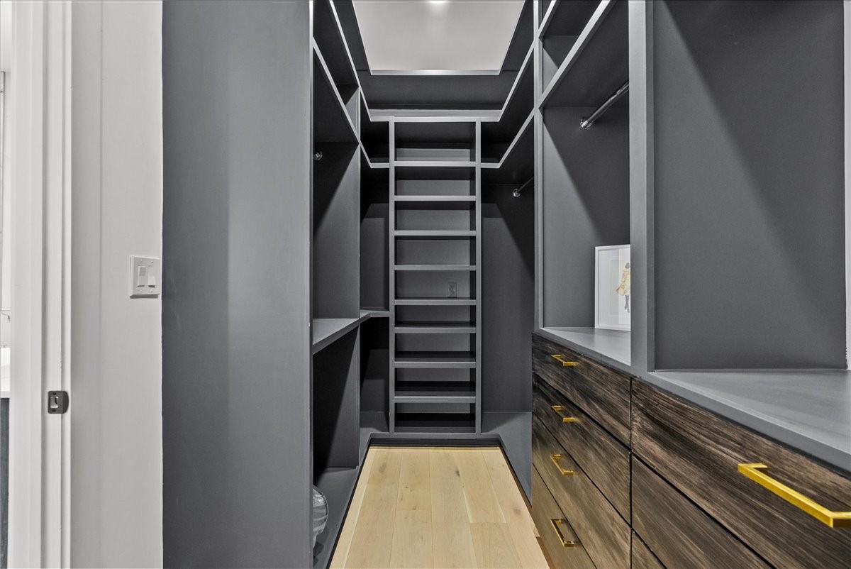 516 Reinerman Street Houston, TX 77007 - Photo 31 of 42 This is a spacious, modern walk-in closet featuring sleek gray shelving and cabinetry with gold handles. It offers ample storage, including multiple shelves, hanging spaces, and drawers, all set against a light wood floor.
