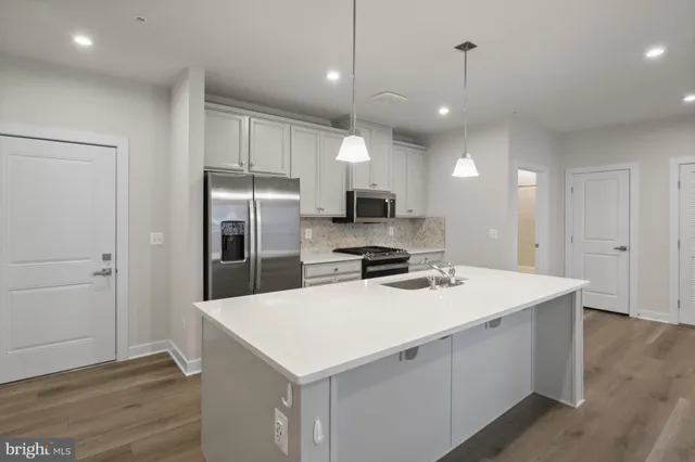 a kitchen that has a sink stainless steel appliances a refrigerator and microwave