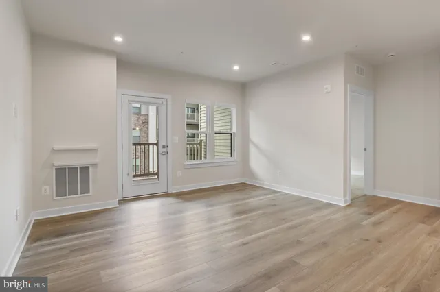 a view of an empty room with wooden floor and windows