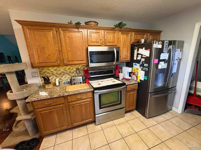 a kitchen with stainless steel appliances kitchen island granite countertop a refrigerator and a stove top oven