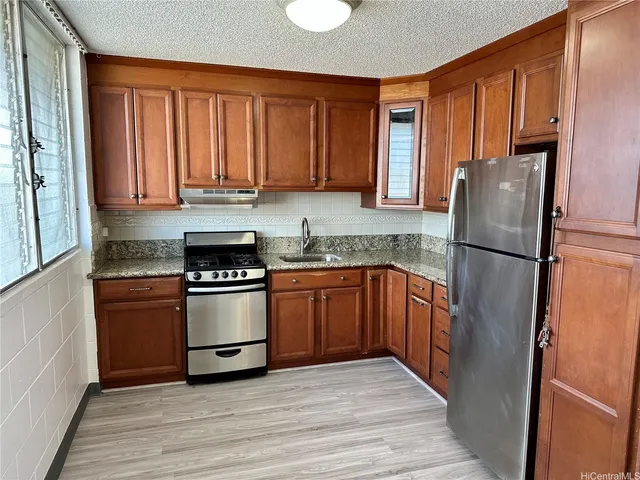 a kitchen with granite countertop wooden floors stainless steel appliances and a window