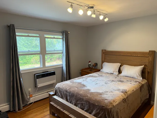 a bedroom with a bed and a flat tv screen on dresser