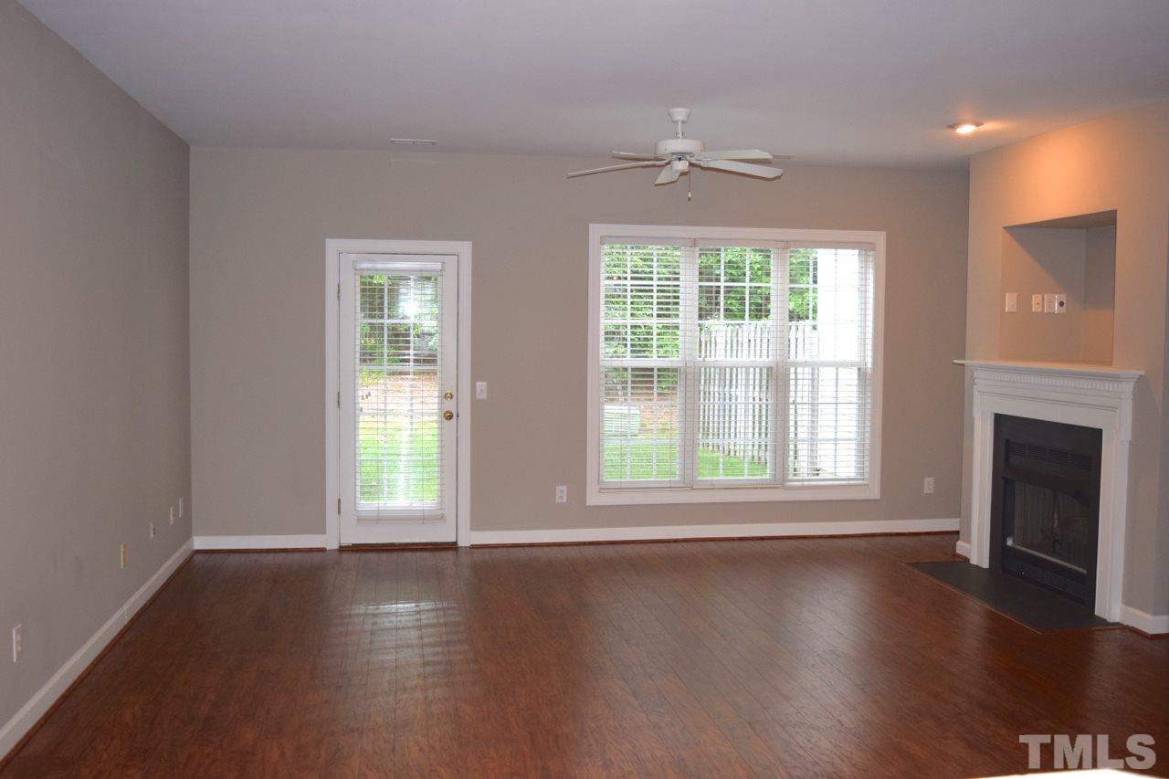 9106 Grassington Way Raleigh, NC 27615 - Photo 5 of 16 an empty room with wooden floor fireplace and windows