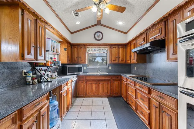 a large kitchen with stainless steel appliances granite countertop a sink and cabinets