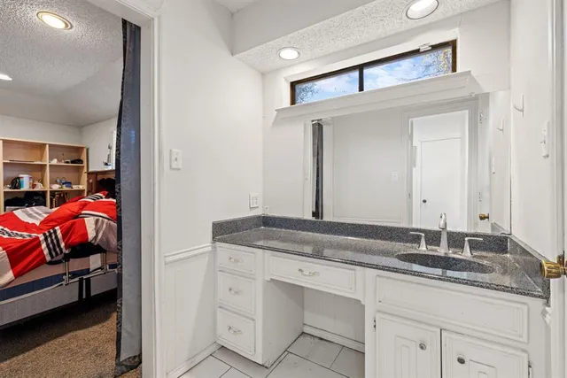 a en suite bathroom with a granite countertop sink and a mirror