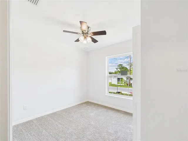 an empty room with a window and a fan