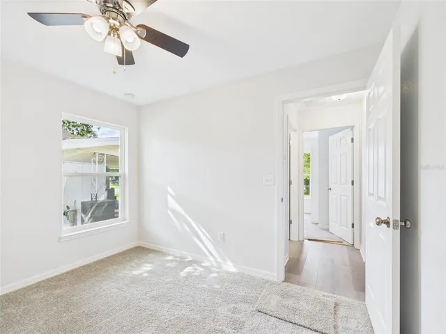 an empty room with a chandelier fan and windows