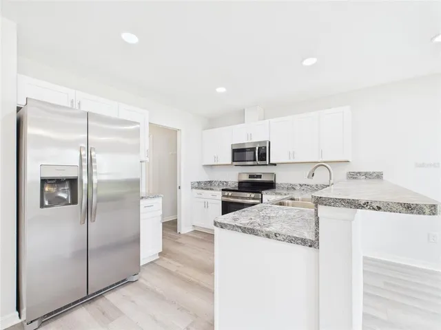 a kitchen with stainless steel appliances granite countertop a refrigerator a stove and a sink