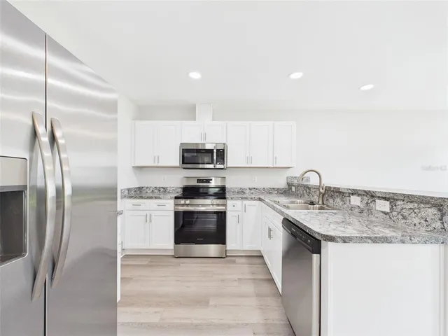 a kitchen with stainless steel appliances granite countertop a sink stove and refrigerator