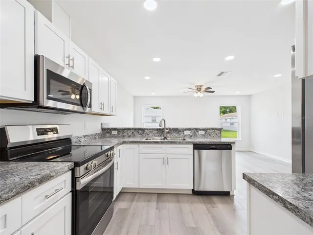 a kitchen with stainless steel appliances granite countertop white cabinets granite counter tops and a wooden floors
