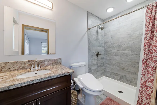 a bathroom with a granite countertop sink a toilet and shower