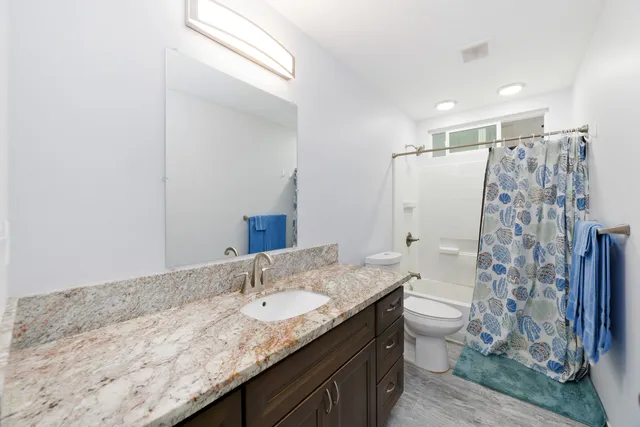 a bathroom with a granite countertop sink toilet and shower