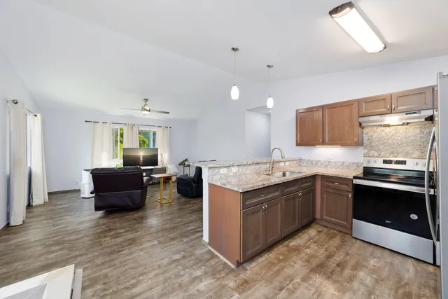 a large kitchen with stainless steel appliances granite countertop a lot of counter space and wooden floor